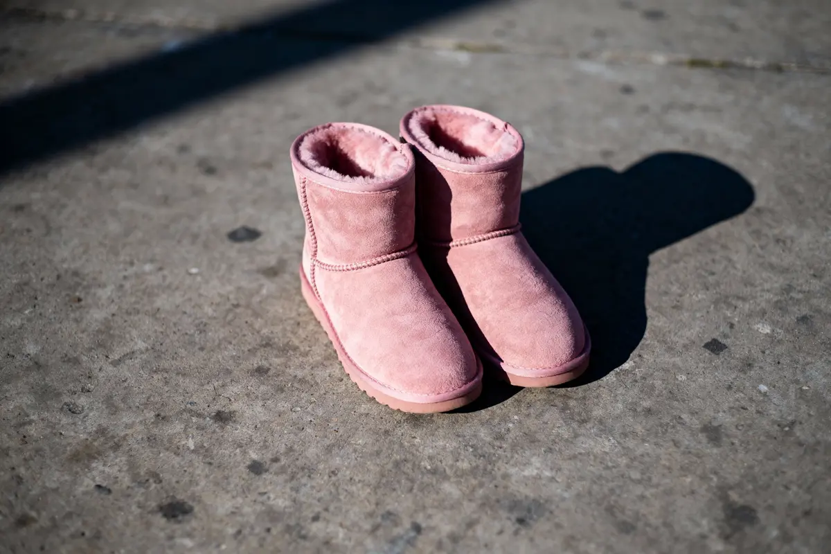Bottes roses en suède, doublure chaude, posées sur sol en béton avec ombres projetées.
