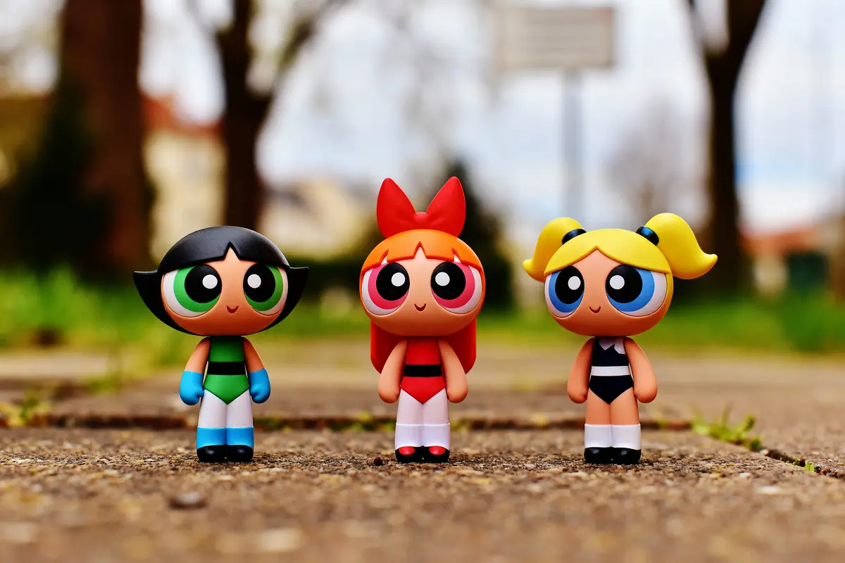 Figurines de trois personnages de dessin animé sur un chemin extérieur, entourées d'arbres flous.