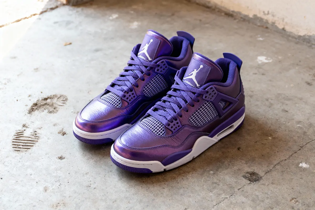 Paire de baskets violettes sur sol en béton, avec logo blanc sur la languette. Fond simple et ombre visible.