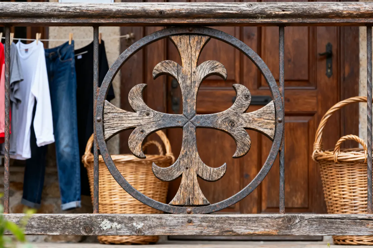 Barrière en fer forgé ornée, paniers en osier, vêtements suspendus, fond de porte en bois marron.