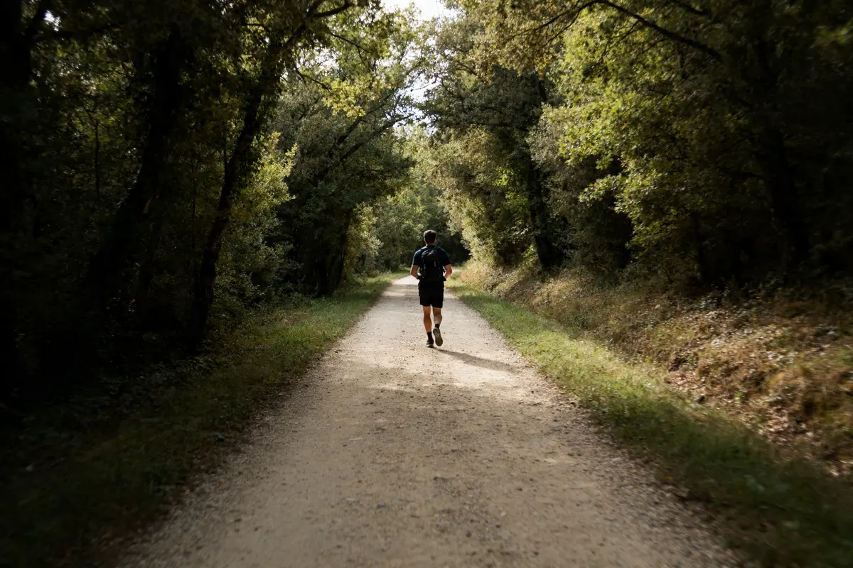 Un coureur sur un chemin boisé illustre 13000 pas en km lors d'un entraînement