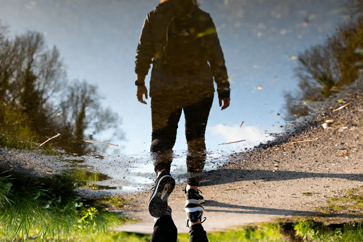 Réflexion dans une flaque d'eau d'une personne marchant 5000 pas en km sur un chemin