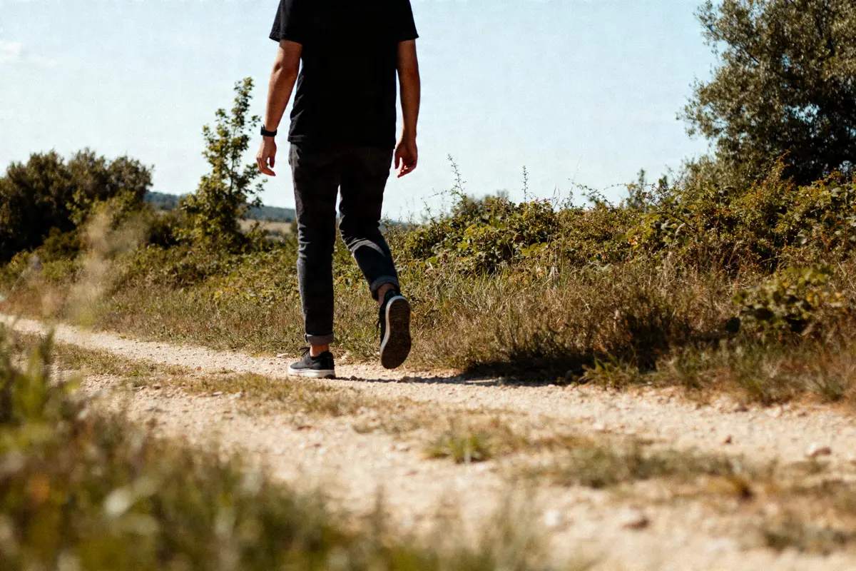 Homme marchant sur chemin nature illustrant 9000 pas en km par jour sans difficultés