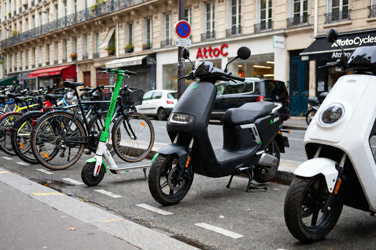 Scooters, vélos et trottinettes AtooCycles stationnés devant un magasin urbain