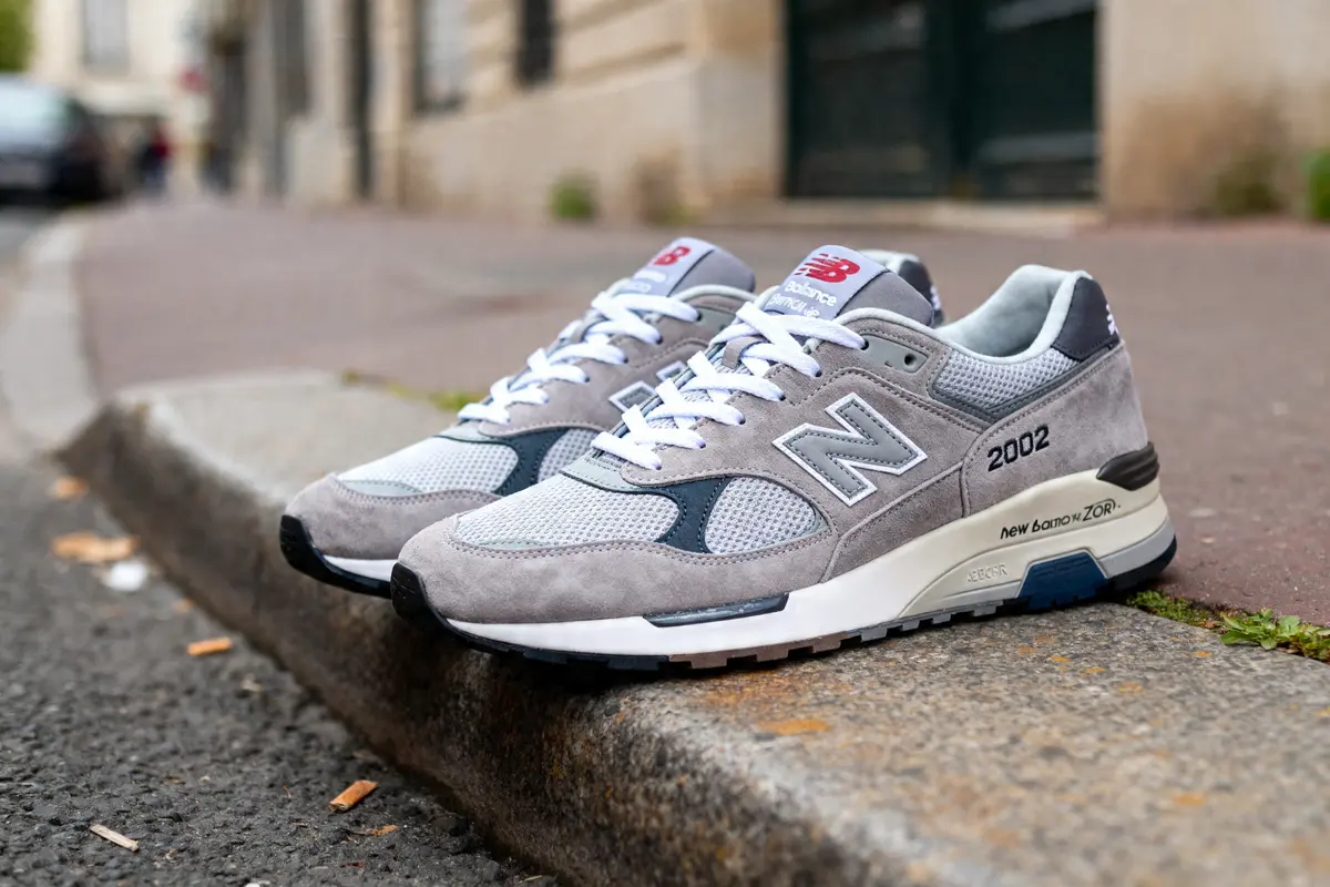 Chaussures New Balance 2002R grises posées sur un trottoir en milieu urbain