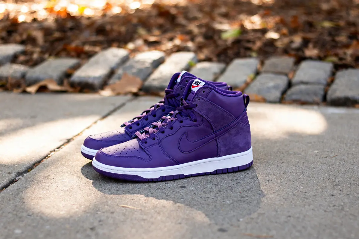 Paire de Nike Dunk High SP Varsity Purple sur un trottoir ensoleillé