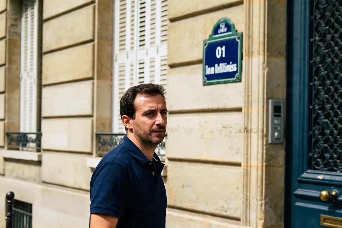 Un homme marche devant une porte avec une plaque d'adresse visible life-magazine.be