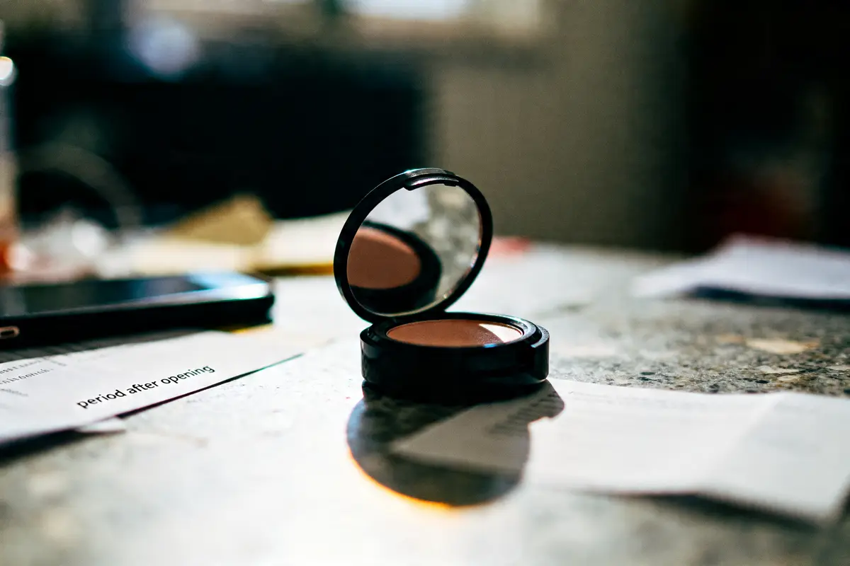 Compact de maquillage ouvert avec miroir sur table, document montre period after opening