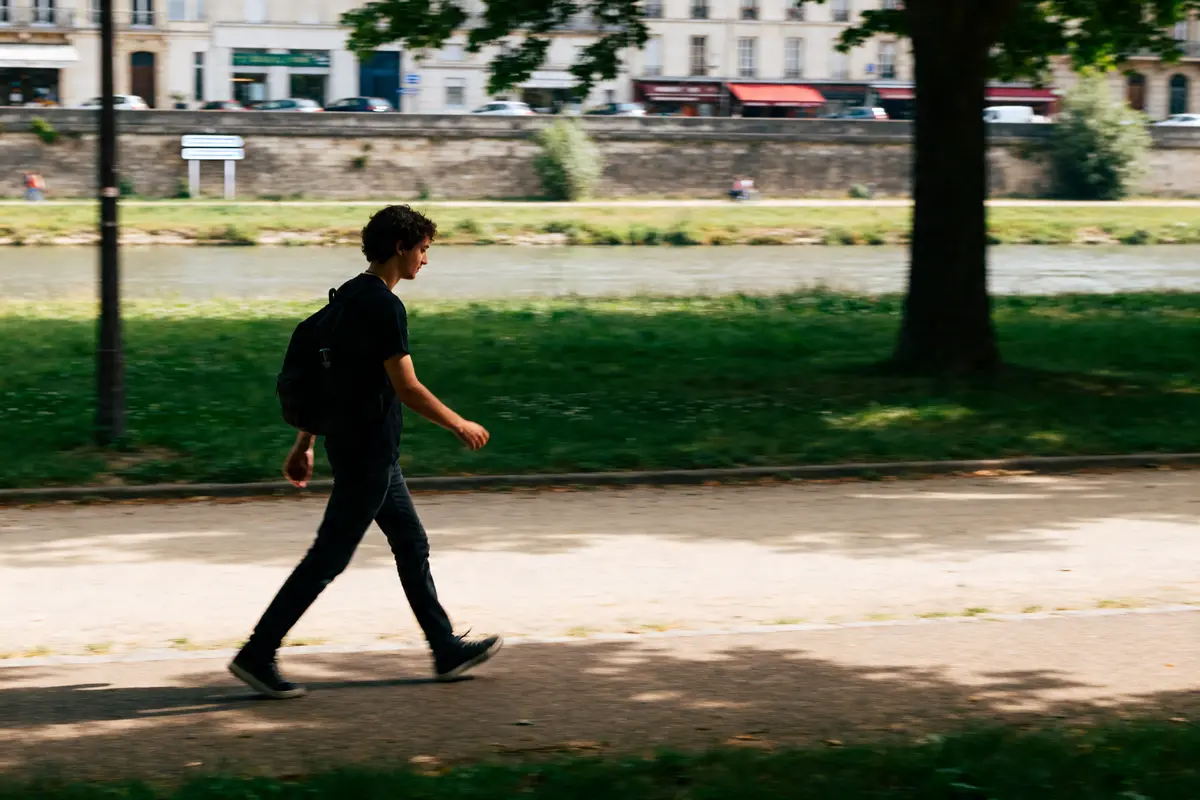 Un jeune homme marche dans un parc, illustrant la vitesse de marche moyenne en ville