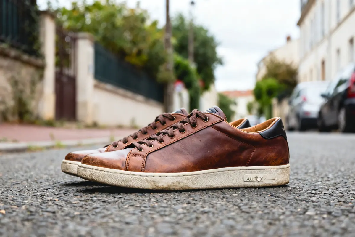 Chaussures Autry en cuir marron posées sur une route résidentielle grise