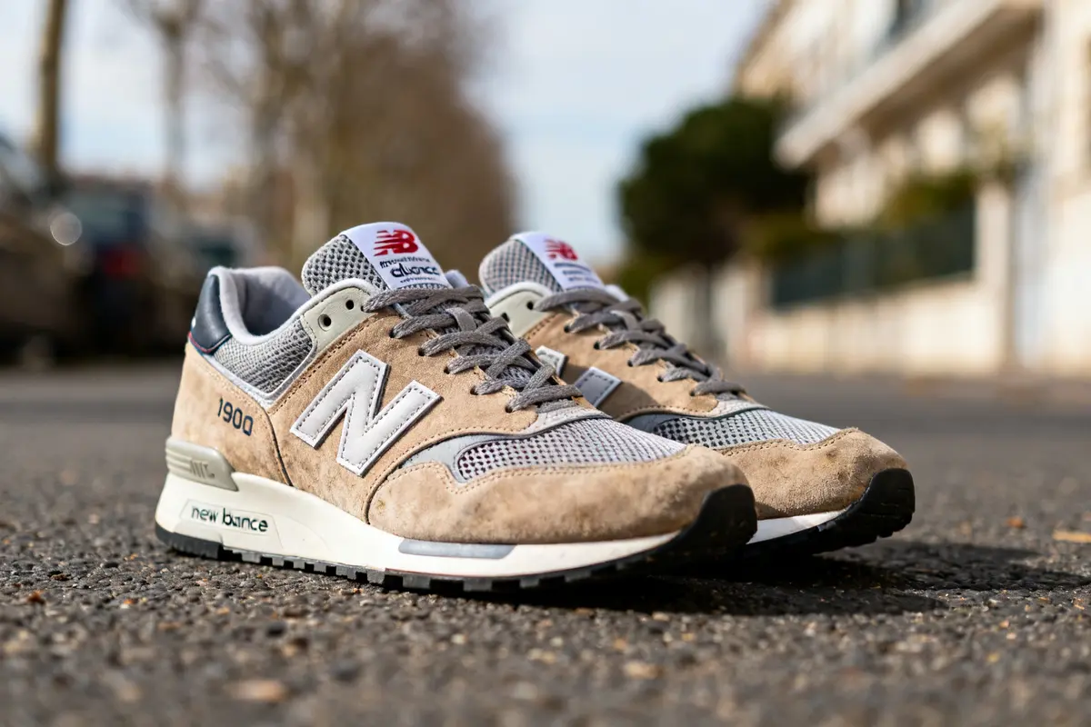 Chaussures New Balance 1906R marron et grises sur une route pavée en extérieur