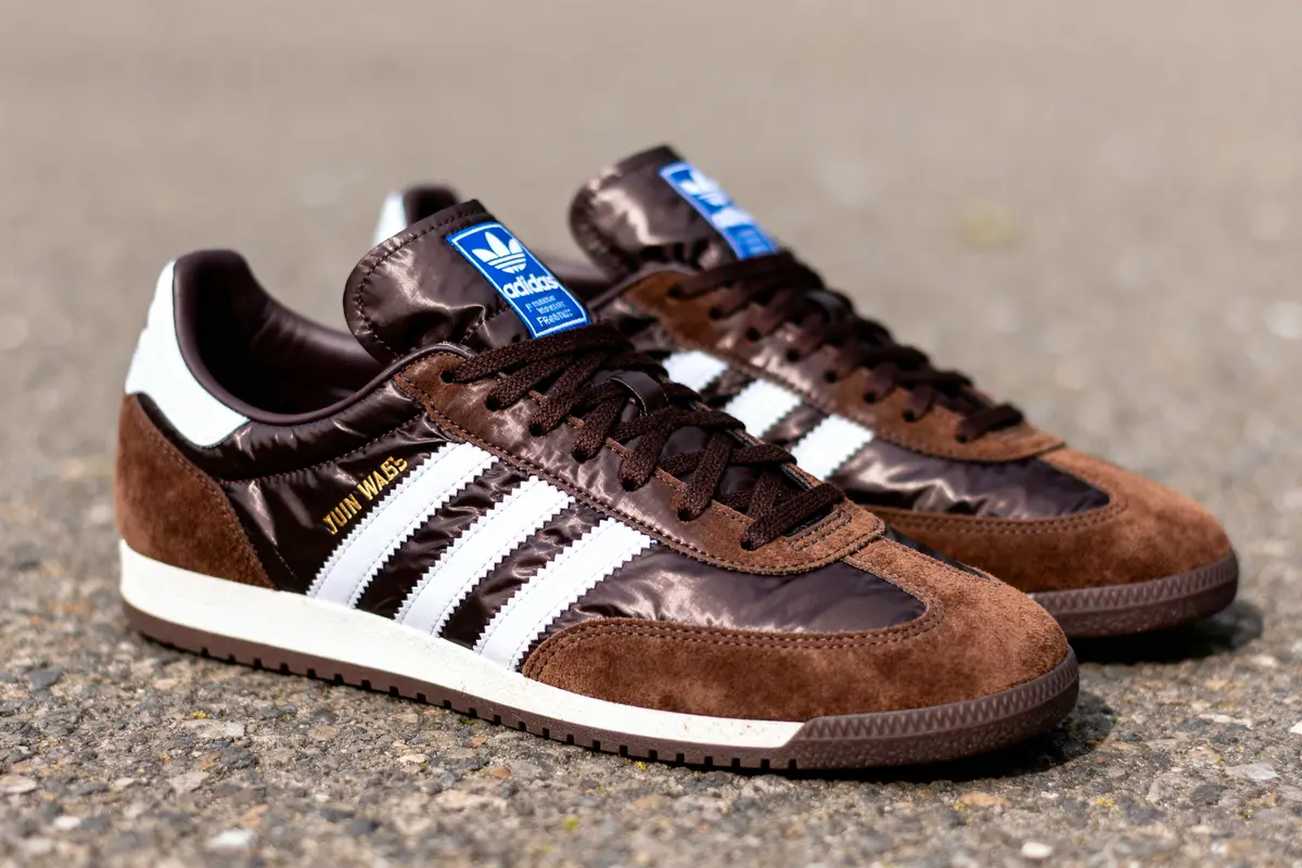 Paire de chaussures Adidas brunes et blanches en daim et nylon, sur sol en béton.