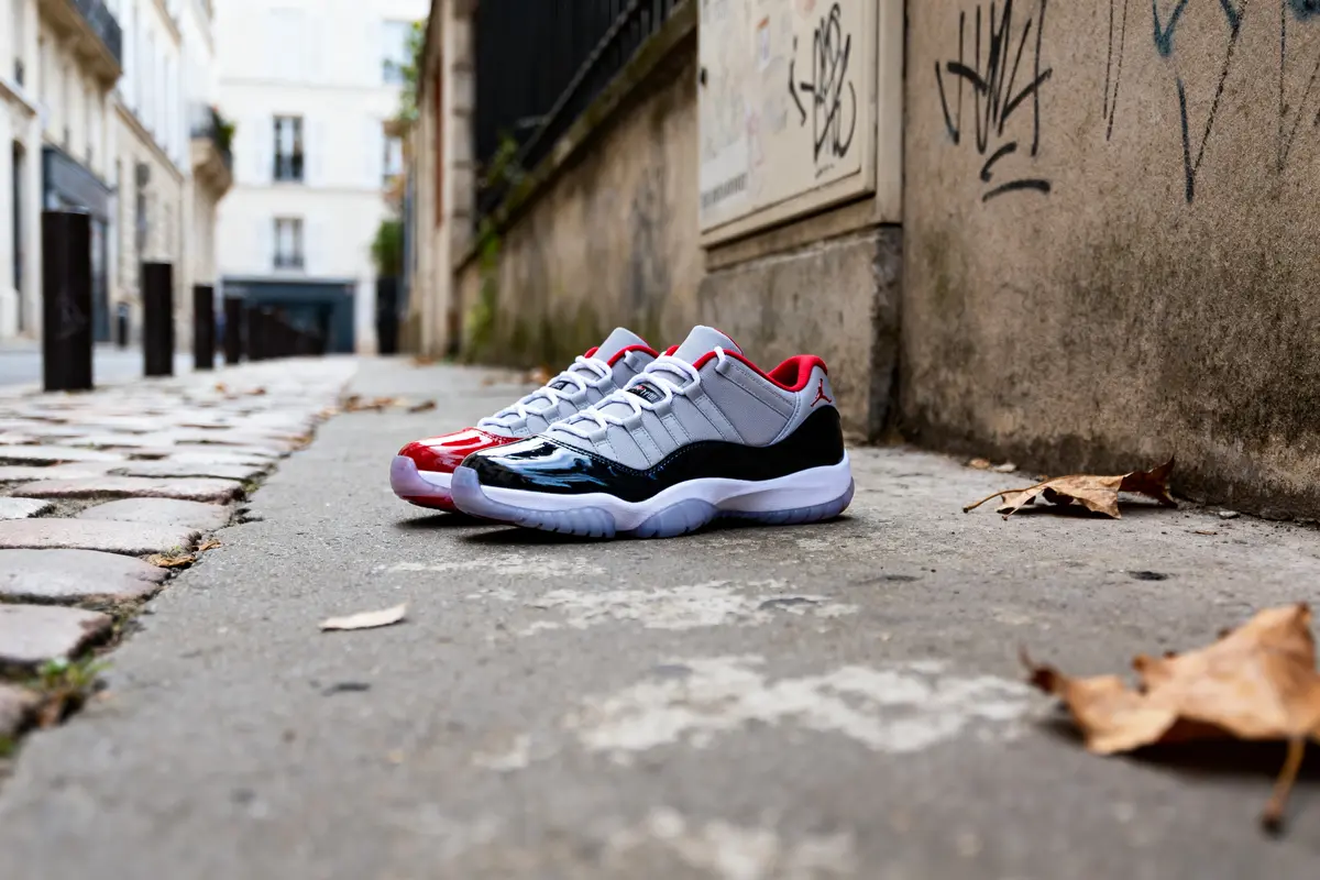 Paire de baskets sur un trottoir urbain, feuilles mortes, mur tagué en arrière-plan.