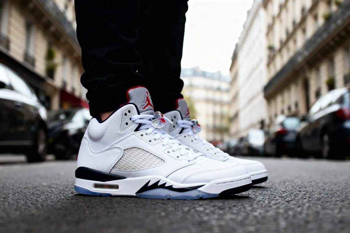 Baskets blanches Air Jordan portées par une personne, debout dans une rue urbaine.