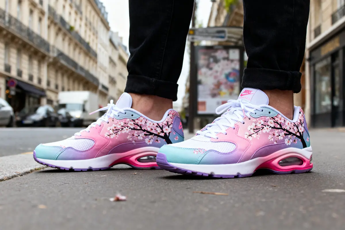 Chaussures colorées avec motif floral portées sur un trottoir urbain devant des bâtiments.