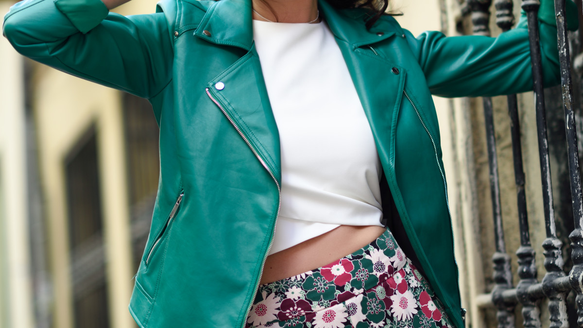 une jeune femme porte une veste en cuir verte ainsi qu'un t shirt blanc