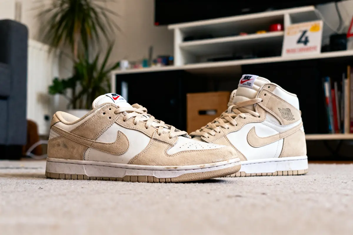 Deux paires de baskets Nike beige sur un tapis, intérieur de salon moderne en arrière-plan.