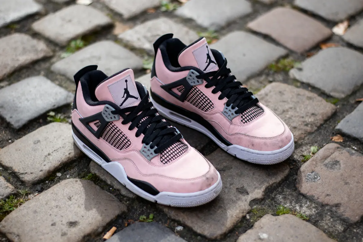 Chaussures de sport roses et noires posées sur un sol pavé.
