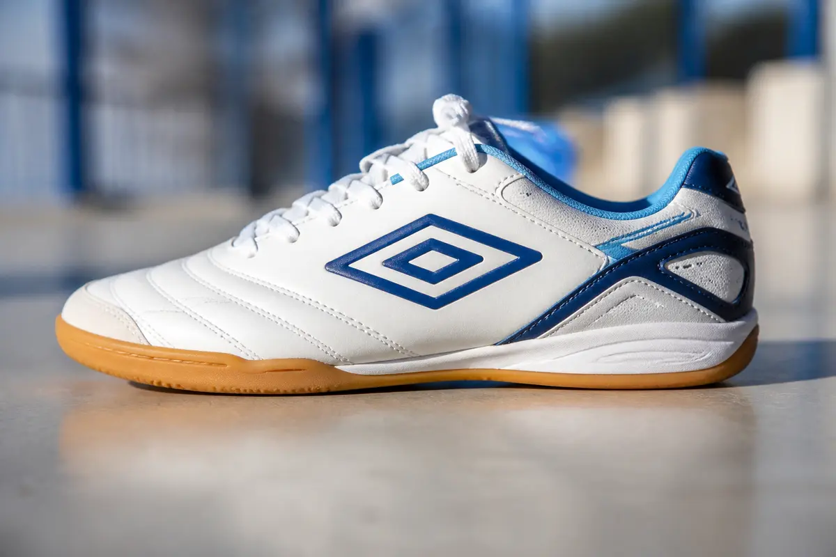 Chaussure de foot en salle blanche et bleue sur sol intérieur lumineux